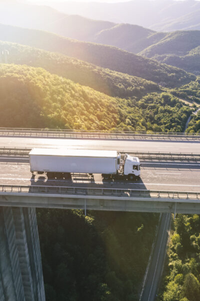 trucks on highway in mountain at sunset aerial view